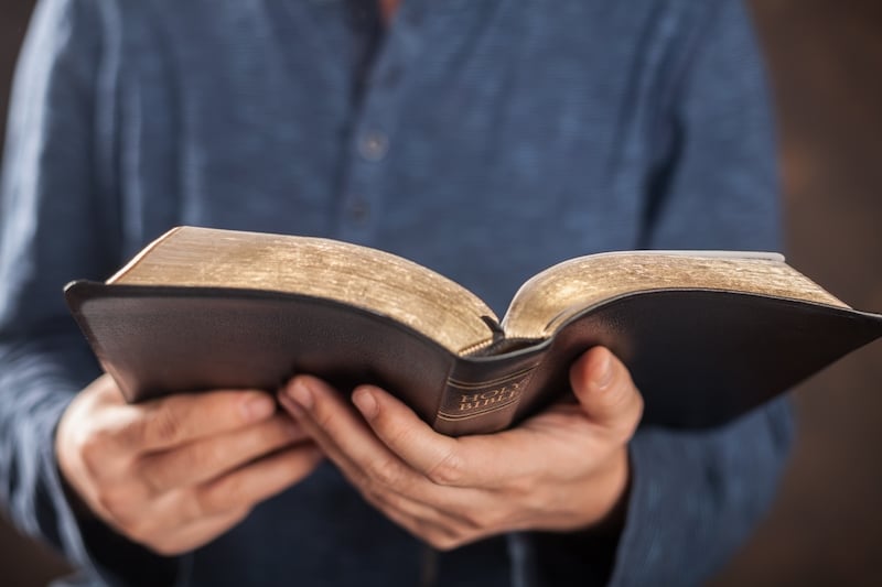 Closeup photo of man holding an open Bible in both hands