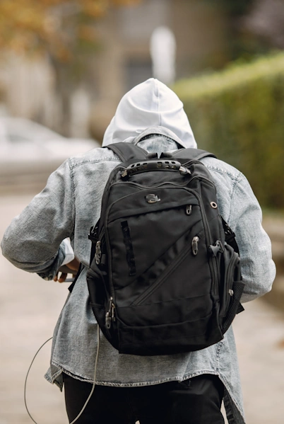 Man in hooded sweatshirt with backpack walking away from camera